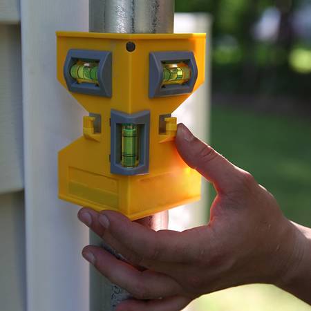 A hand is fixing the yellow post level on the metal pipeline.
